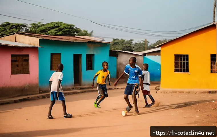 코트디부아르 유명 축구 선수 - A vibrant street football scene in an Ivorian neighborhood during golden hour, showing diverse child...